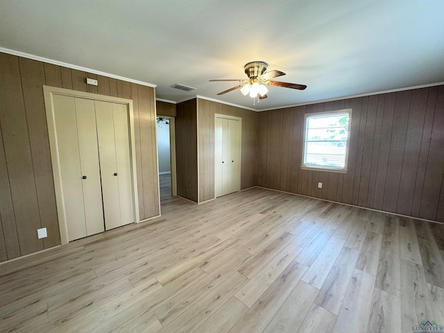1506 Scenic Dr, Longview, TX 75604 - unfurnished bedroom with two closets, crown molding, light wood-type flooring, wooden walls, and a ceiling fan