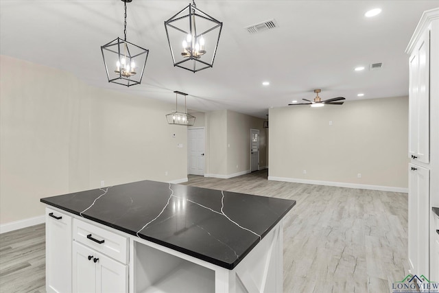 kitchen featuring decorative light fixtures, white cabinetry, a center island, ceiling fan, and light wood-type flooring