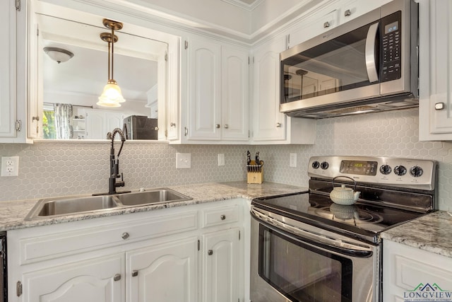 10887 Knollwood Dr, Tyler, TX 75703 - kitchen featuring appliances with stainless steel finishes, a sink, backsplash, white cabinetry, and decorative light fixtures