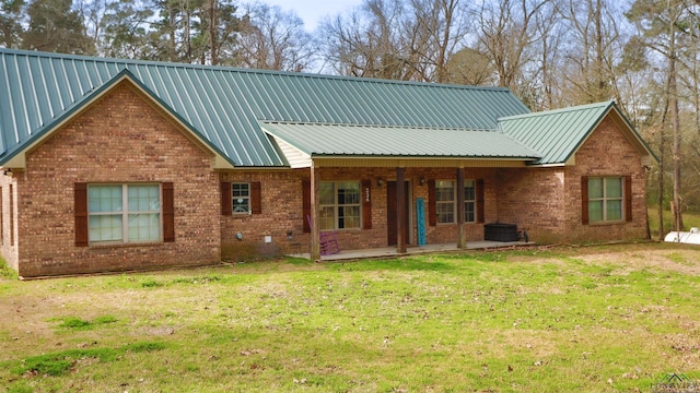 rear view of property featuring metal roof, brick siding, and a lawn