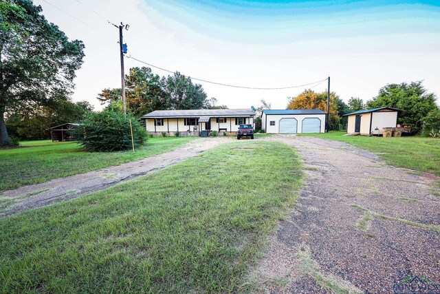 single story home with a porch, a garage, an outdoor structure, and a front lawn