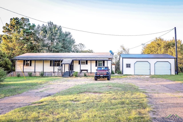 ranch-style home featuring a front yard, covered porch, an outdoor structure, and a garage