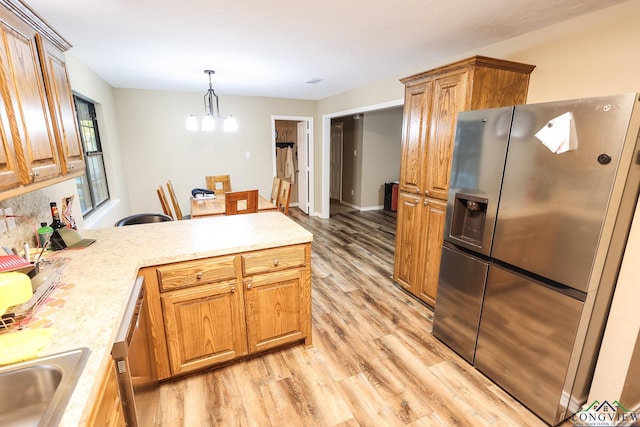 kitchen with sink, hanging light fixtures, stainless steel fridge, a notable chandelier, and light hardwood / wood-style floors