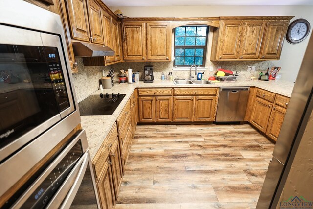 kitchen with backsplash, sink, light hardwood / wood-style flooring, and appliances with stainless steel finishes