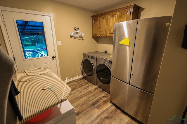 laundry room with washer and dryer, wood-type flooring, and cabinets