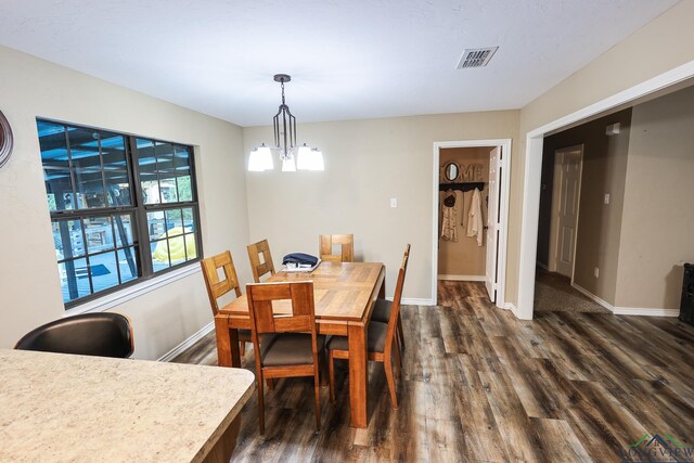 dining space featuring dark hardwood / wood-style flooring and an inviting chandelier