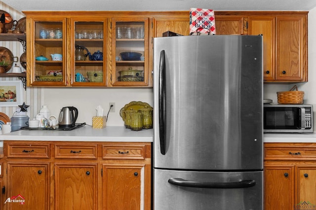 kitchen with brown cabinetry, light countertops, and appliances with stainless steel finishes