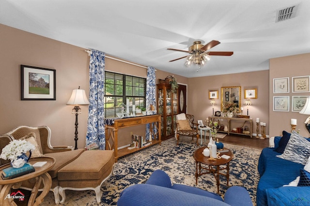 living room featuring baseboards, wood finished floors, visible vents, and ceiling fan