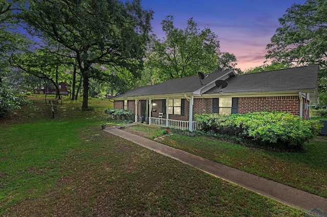 single story home featuring a lawn and brick siding