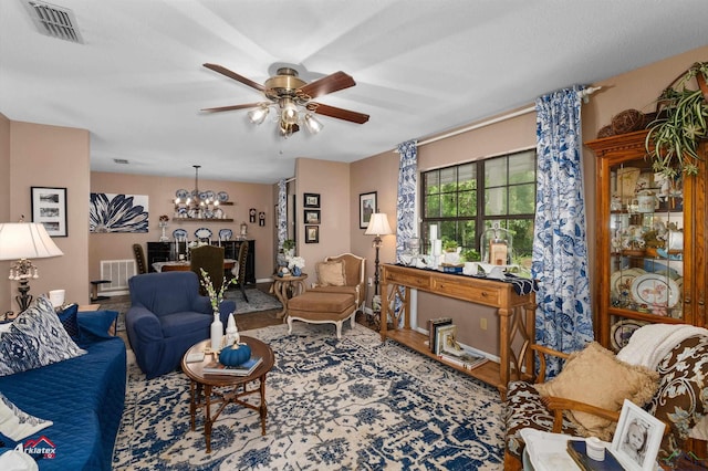 living room featuring ceiling fan with notable chandelier, baseboards, and visible vents