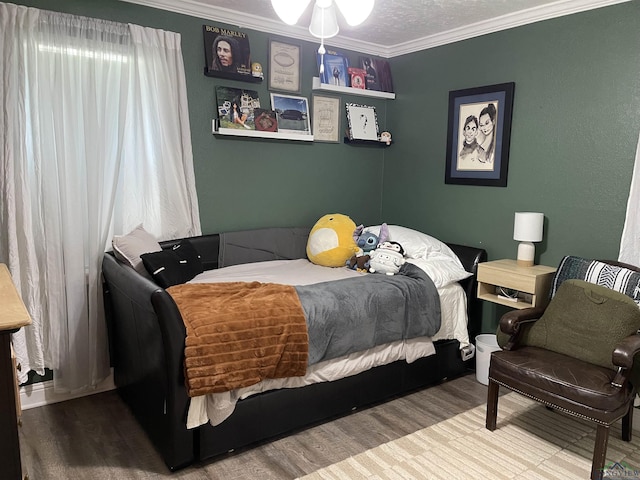 bedroom featuring wood-type flooring, a textured ceiling, and ornamental molding