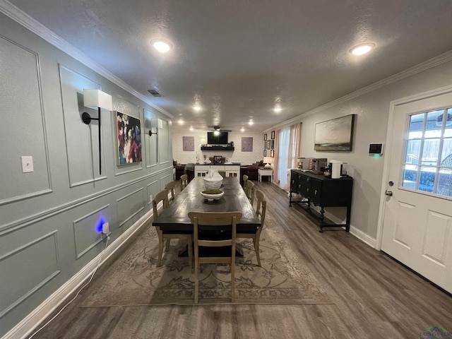 dining area with hardwood / wood-style flooring, ornamental molding, and a textured ceiling