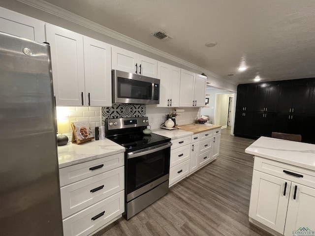 kitchen featuring decorative backsplash, stainless steel appliances, crown molding, white cabinets, and dark hardwood / wood-style floors