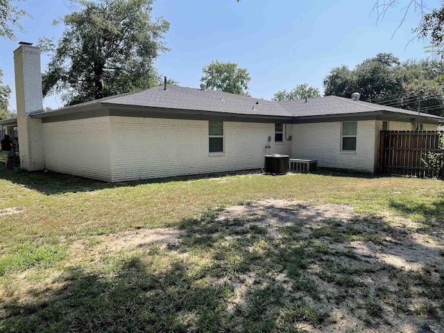 rear view of property with a lawn and cooling unit