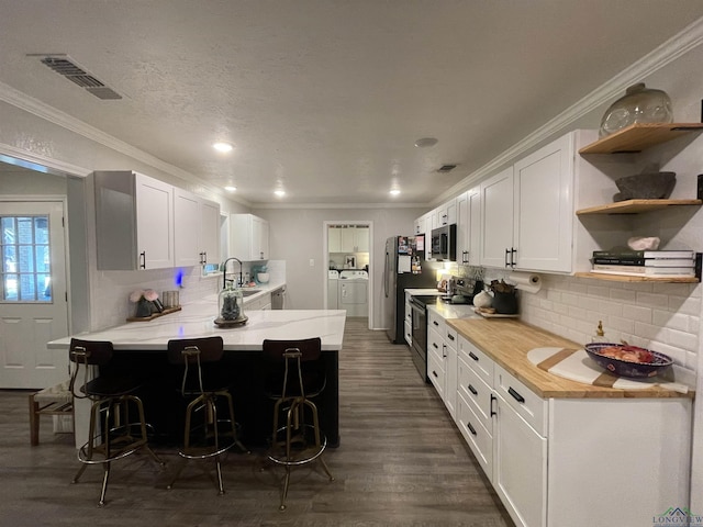 kitchen featuring kitchen peninsula, a kitchen breakfast bar, tasteful backsplash, stainless steel appliances, and white cabinetry