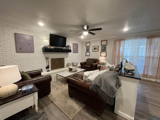 living room with a fireplace, ceiling fan, dark wood-type flooring, and brick wall