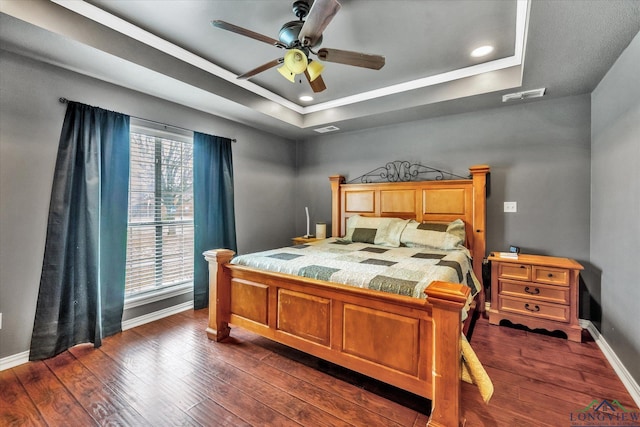 bedroom with a raised ceiling, ceiling fan, and dark hardwood / wood-style flooring