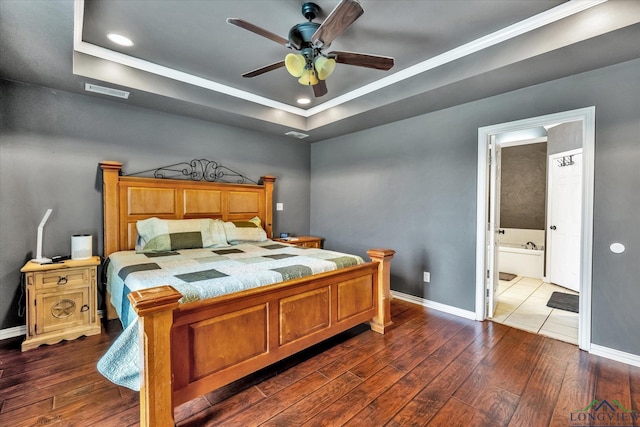 bedroom featuring ensuite bathroom, a raised ceiling, ceiling fan, crown molding, and dark wood-type flooring