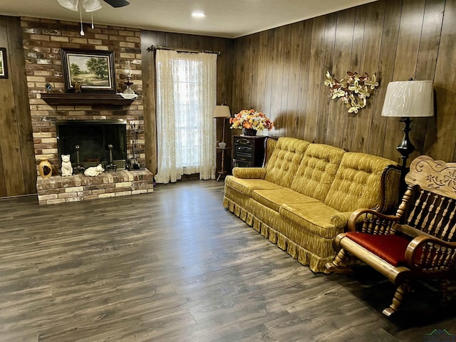 living area with dark wood-style floors, wood walls, and a fireplace