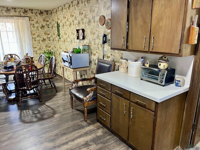 kitchen featuring wallpapered walls, stainless steel microwave, light countertops, and dark wood-style flooring