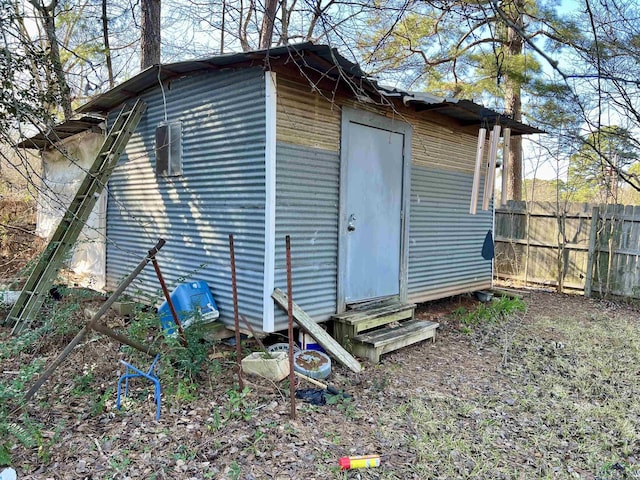 view of outbuilding featuring entry steps and fence