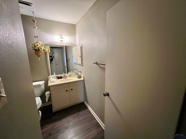 bathroom with toilet, wood finished floors, vanity, and baseboards