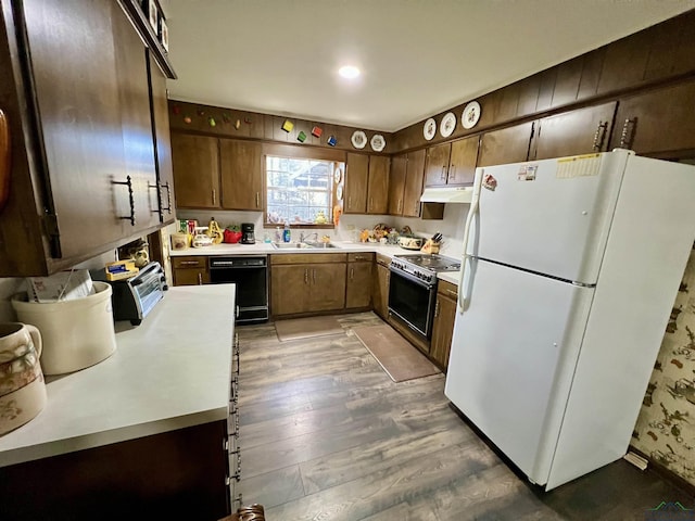 kitchen featuring range with electric stovetop, a sink, black dishwasher, light countertops, and freestanding refrigerator