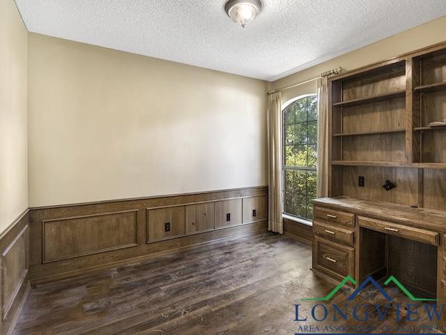 1204 Marigold Ln, Longview, TX 75604 - unfurnished office featuring a textured ceiling, wainscoting, and dark wood-style flooring