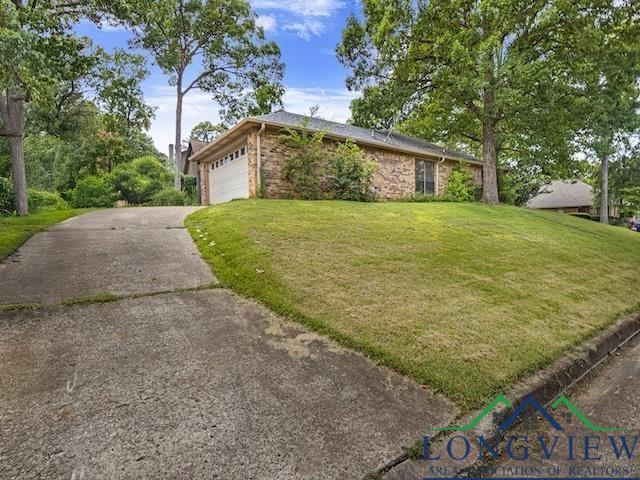 1204 Marigold Ln, Longview, TX 75604 - view of front of home featuring a front lawn, concrete driveway, an attached garage, and brick siding