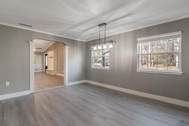 unfurnished dining area with ceiling fan with notable chandelier, light wood-type flooring, and crown molding