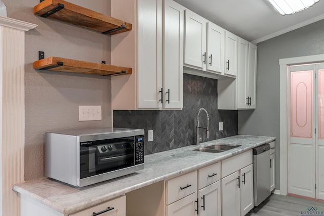 kitchen with crown molding, sink, decorative backsplash, appliances with stainless steel finishes, and white cabinetry