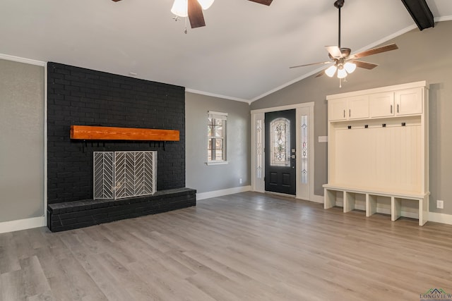 interior space with ceiling fan, ornamental molding, vaulted ceiling, a fireplace, and light wood-type flooring