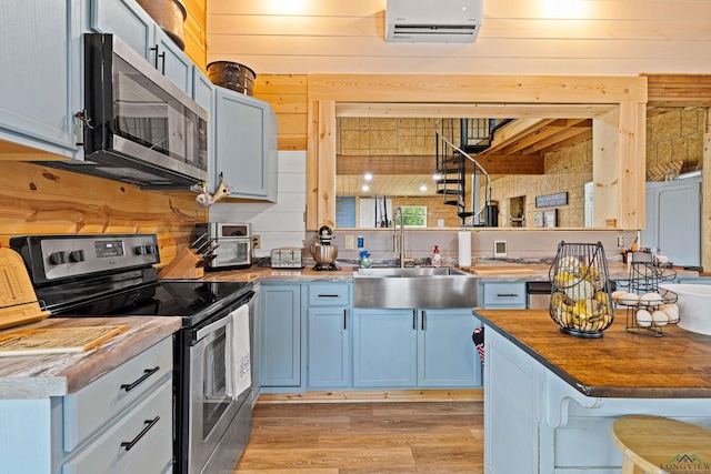 kitchen featuring wooden counters, sink, wooden walls, appliances with stainless steel finishes, and a wall mounted AC