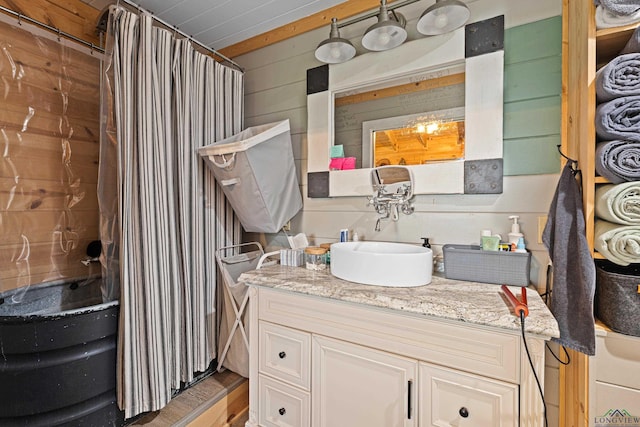 bathroom with wood walls, vanity, and walk in shower