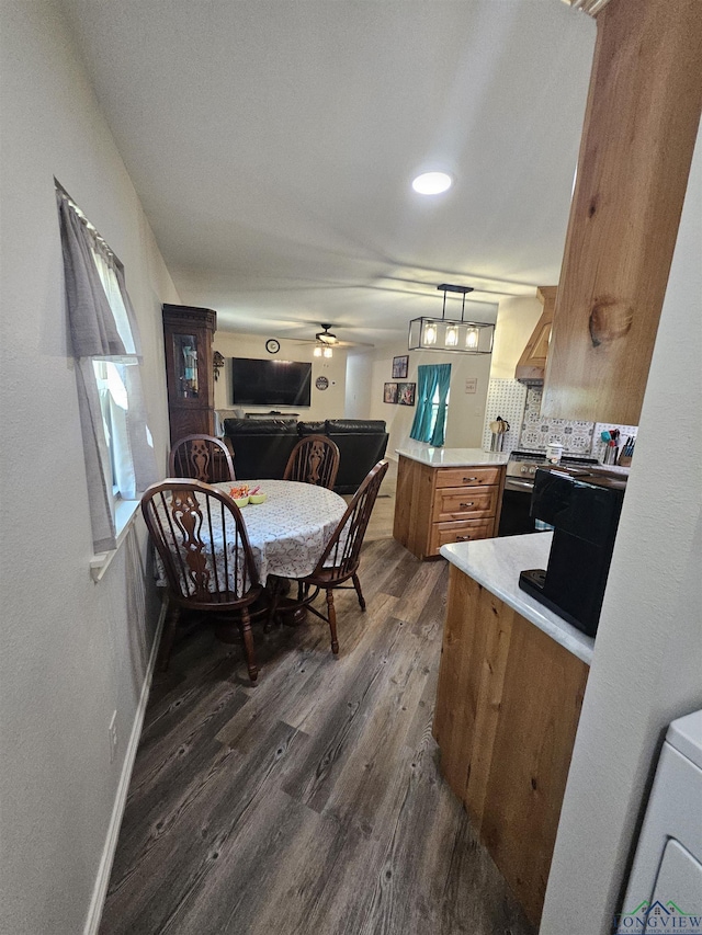 kitchen featuring kitchen peninsula, ceiling fan, dark wood-type flooring, electric range, and decorative light fixtures