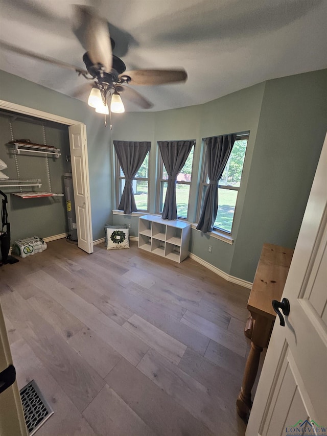 unfurnished bedroom with hardwood / wood-style floors, electric water heater, a closet, and ceiling fan