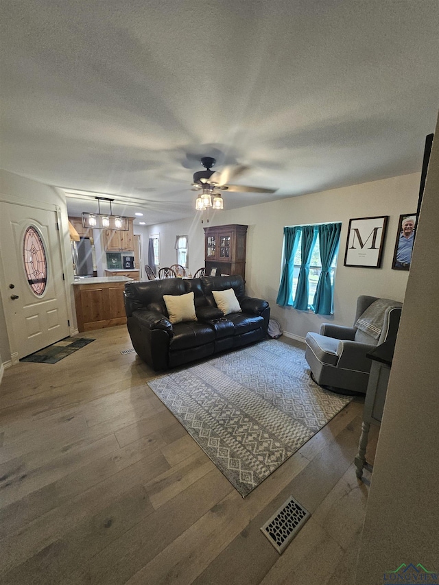 living room with hardwood / wood-style floors, ceiling fan, a healthy amount of sunlight, and a textured ceiling