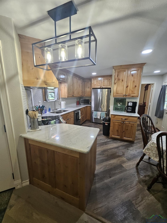 kitchen with kitchen peninsula, appliances with stainless steel finishes, decorative light fixtures, and tasteful backsplash