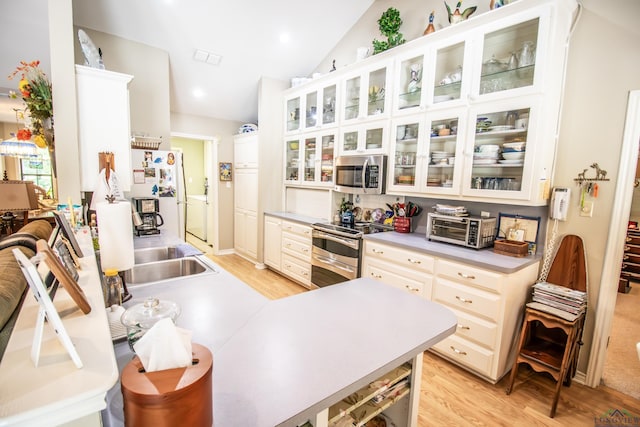 514 Buckeye Hill Rd, Karnack, TX 75661 - kitchen with appliances with stainless steel finishes, light wood finished floors, lofted ceiling, light countertops, and glass insert cabinets