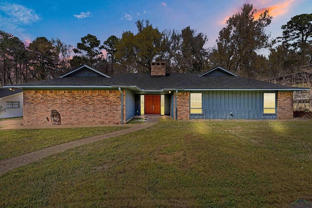 ranch-style home featuring board and batten siding, brick siding, a chimney, and a front yard
