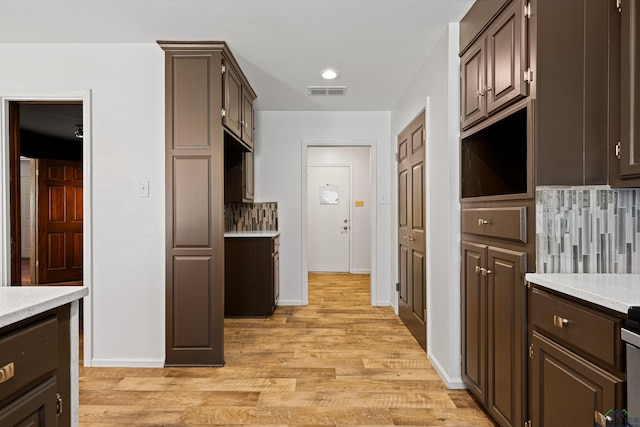 kitchen featuring decorative backsplash, dark brown cabinetry, light wood-style floors, and visible vents