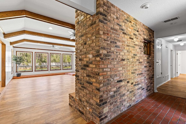 hall featuring baseboards, a textured ceiling, wood finished floors, and vaulted ceiling