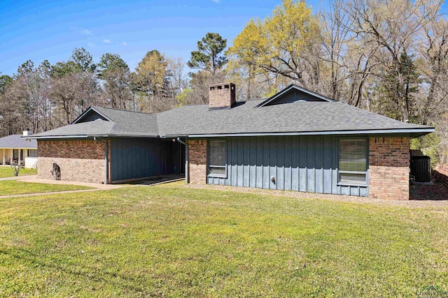 view of front facade with brick siding, a chimney, a front lawn, and roof with shingles
