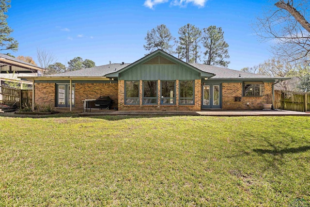 rear view of house with fence, brick siding, and a lawn