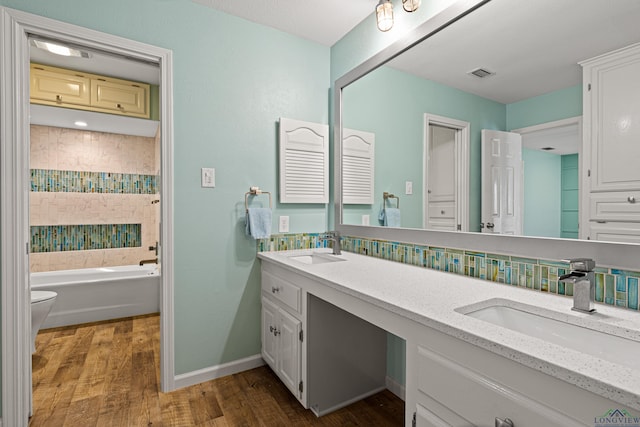 full bath with double vanity, visible vents, wood finished floors, and a sink