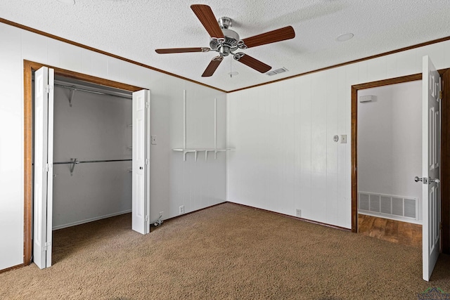 unfurnished bedroom with visible vents, a textured ceiling, ornamental molding, and carpet flooring