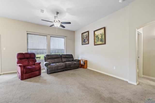 carpeted living room with baseboards, visible vents, arched walkways, and ceiling fan