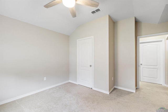 unfurnished bedroom featuring baseboards, vaulted ceiling, visible vents, and light colored carpet