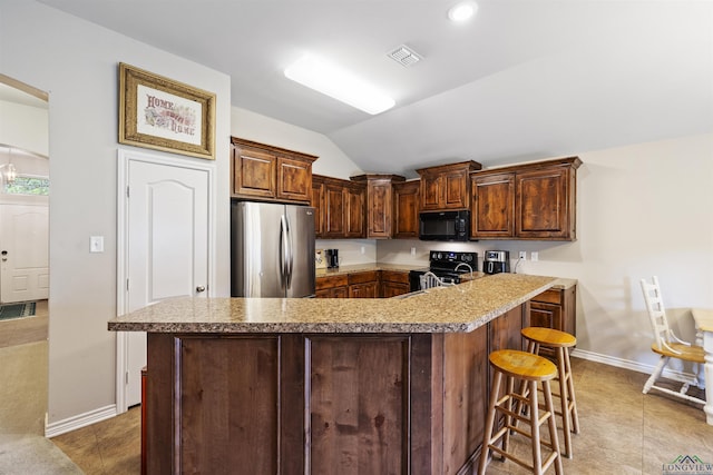 kitchen featuring lofted ceiling, a kitchen breakfast bar, visible vents, baseboards, and black appliances