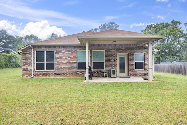 rear view of house featuring brick siding, a yard, and a patio